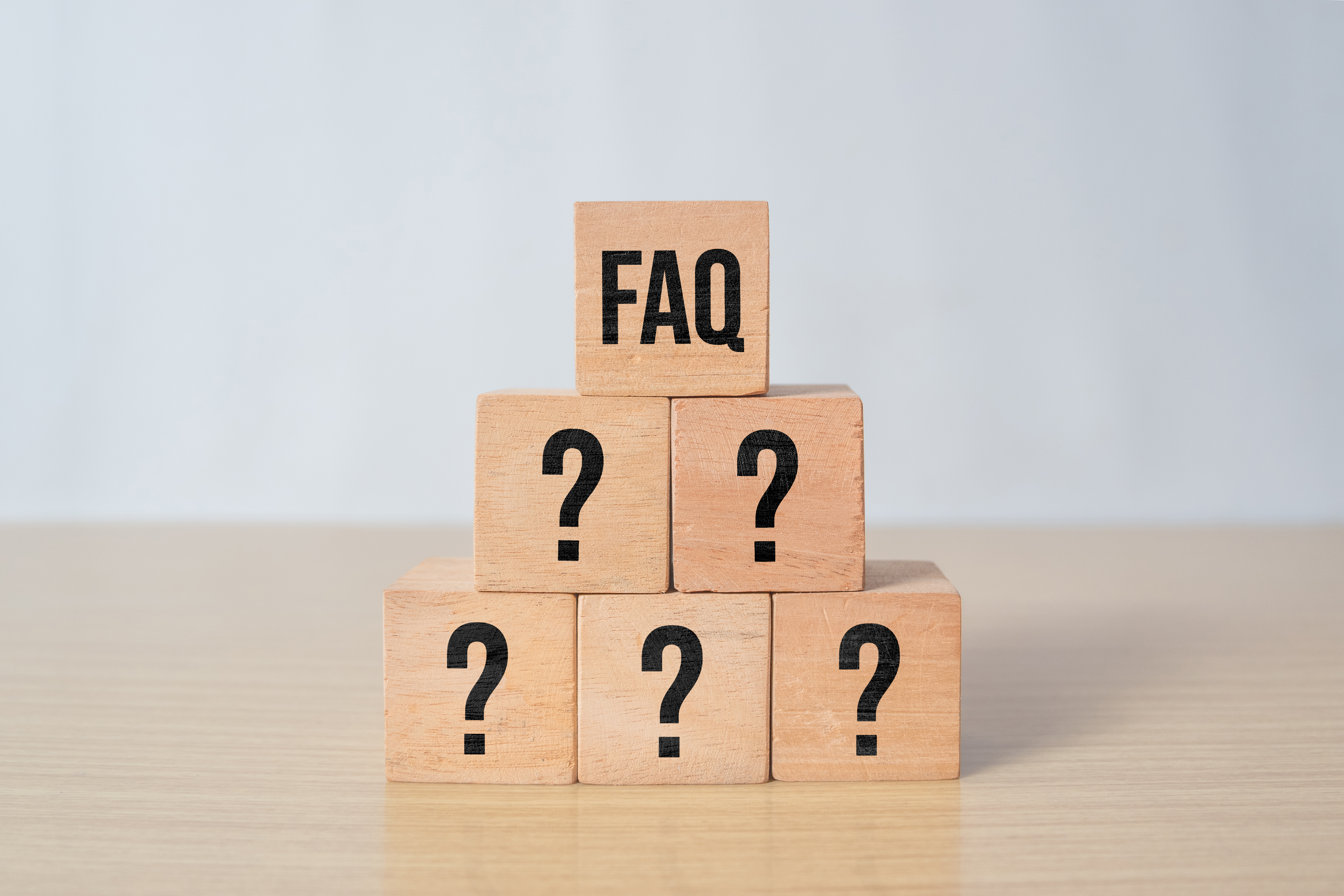 FAQと書かれた木製ブロックとクエスチョンマーク